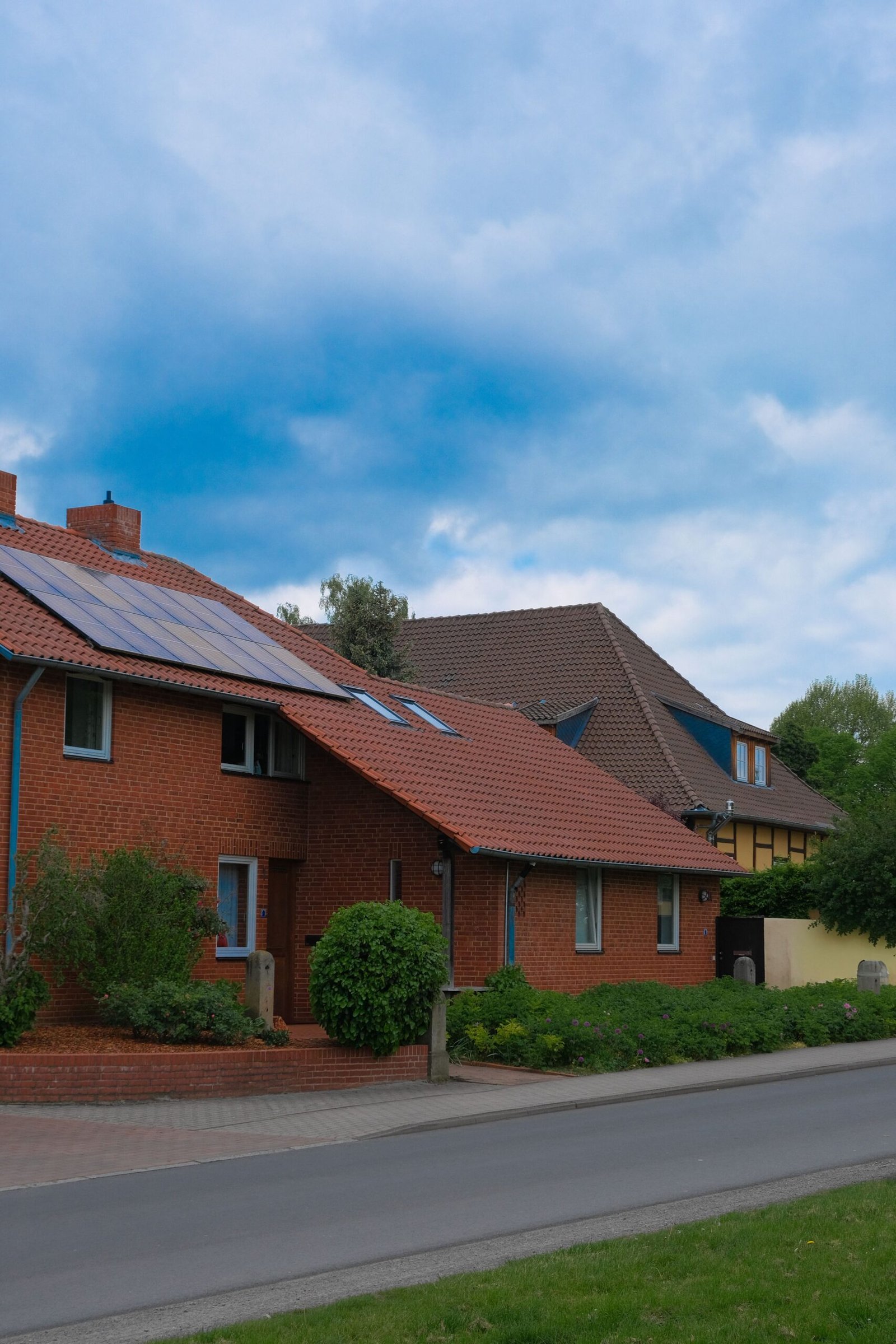 Brick houses with solar panels on the roofs under a blue sky, showing home energy efficiency upgrades