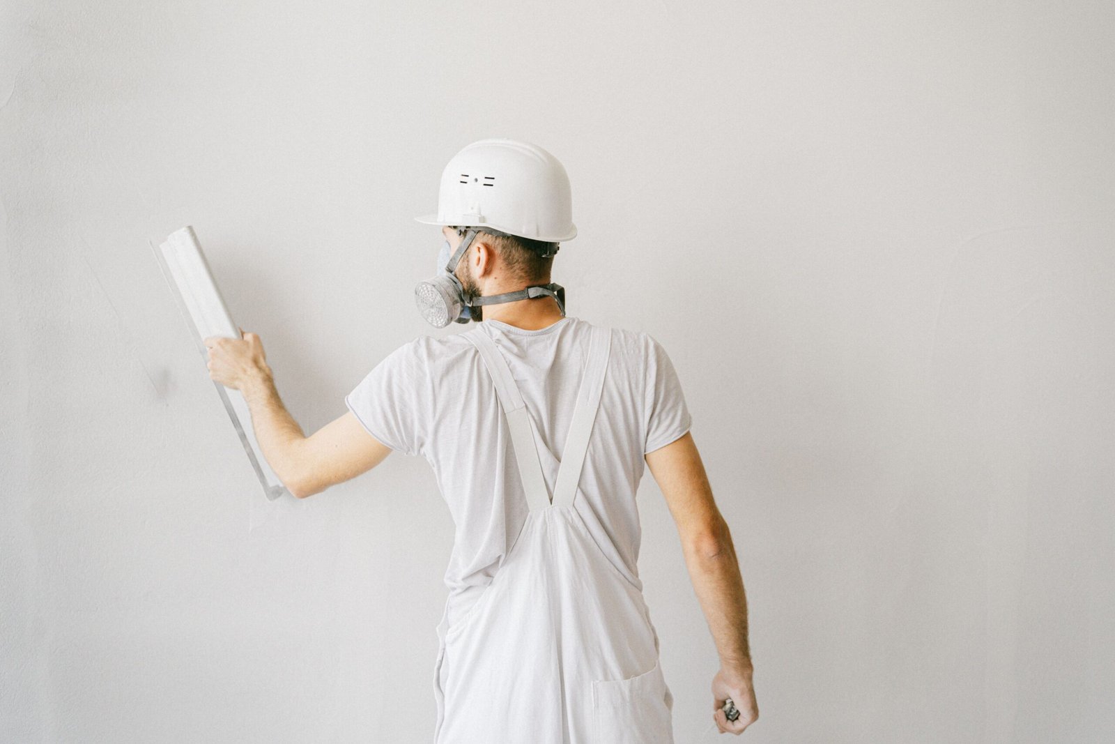 Construction worker in protective gear plastering a wall during home repair work